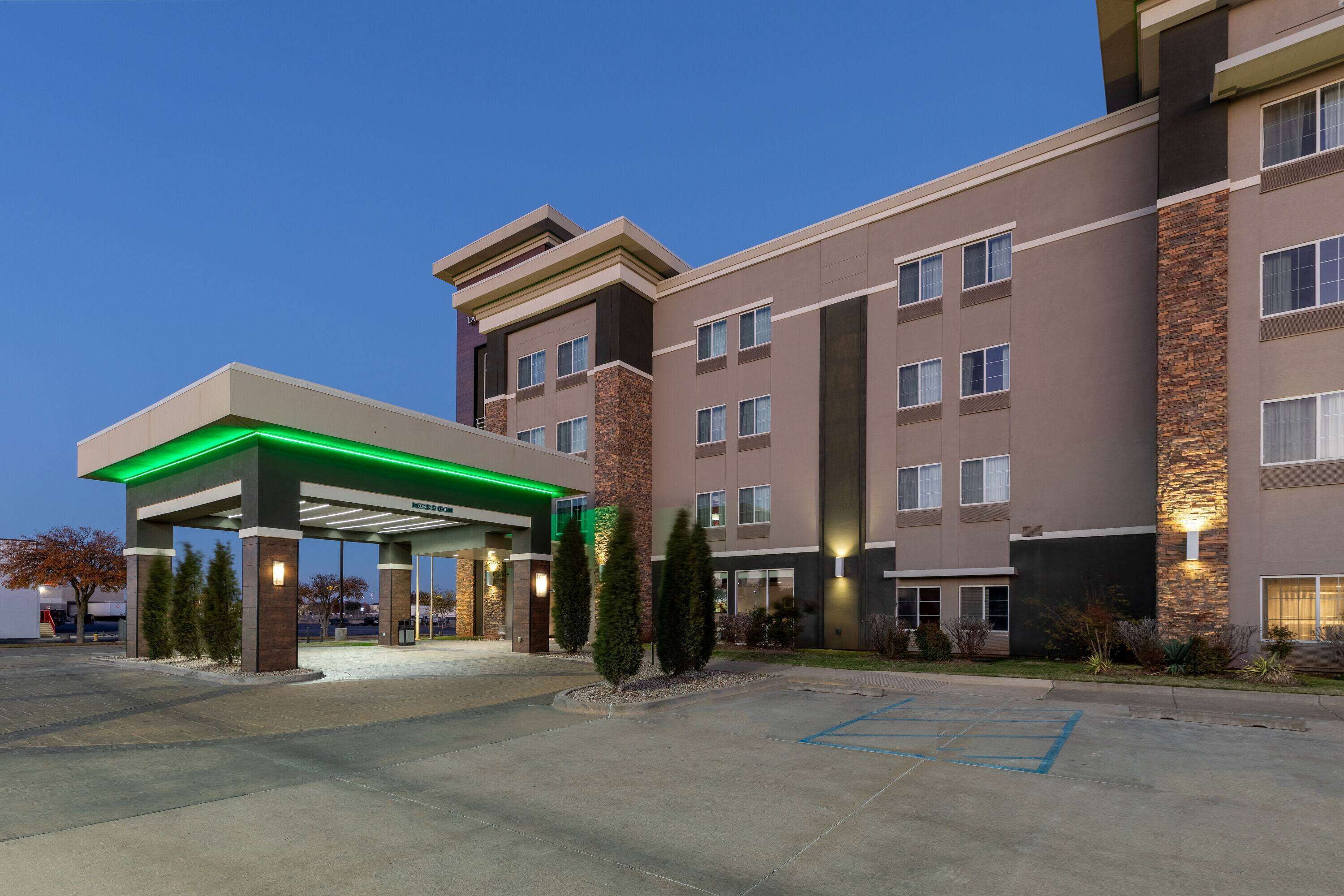 A multi-story hotel with a covered parking area and a gas station.