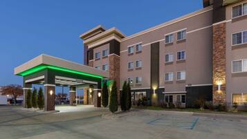 A multi-story hotel with a covered parking area and a gas station.