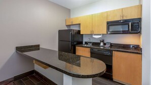 A compact kitchen with a granite countertop, stainless steel appliances, and wooden cabinets.