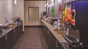 A modern kitchen with a long counter, various appliances, and a tiled backsplash.
