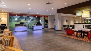 A hotel lobby with a reception desk, seating area, and a large wall mural.