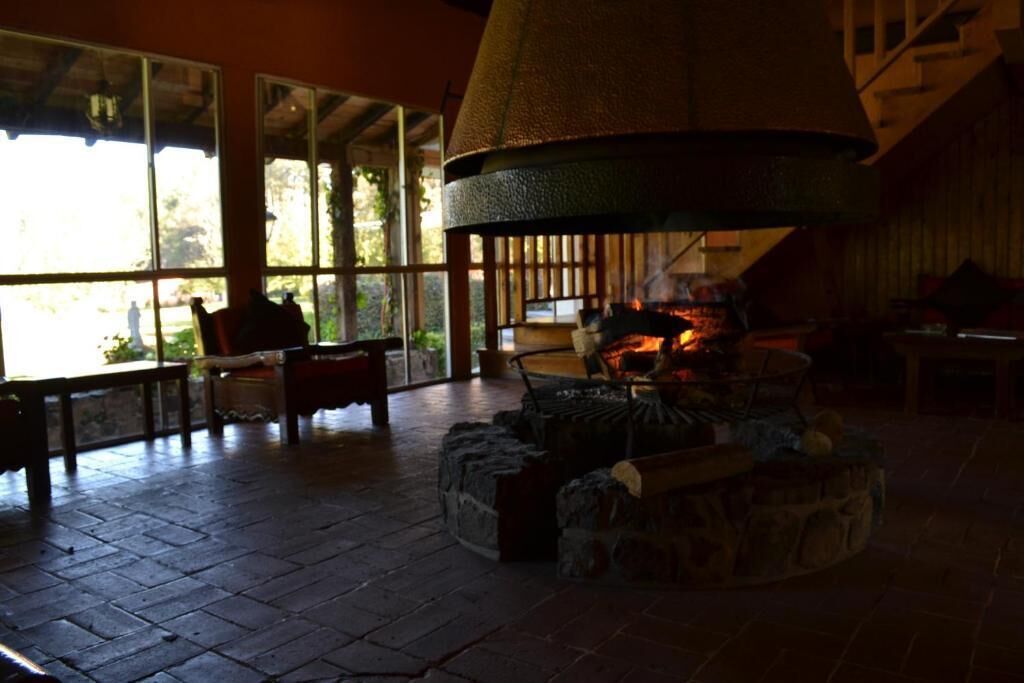 A room with a fireplace, large windows, and a stone fireplace surround.