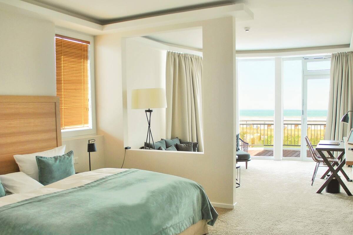 Ein Hotelzimmer mit Bett, Schreibtisch, Stuhl und Meerblick.