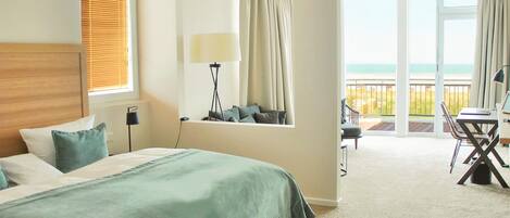 Una habitación de hotel con cama, escritorio, silla y vista al océano.