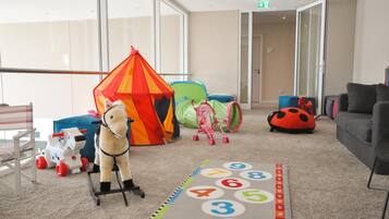 A children's play area with a tent, a toy horse, a number mat, and a ladybug cushion.