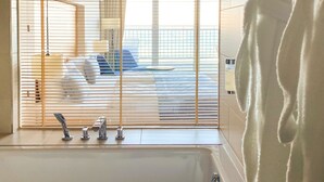 A bathroom with a bathtub, a sink with faucets, and a window with blinds. - SeeHuus Lifestyle Hotel (Timmendorfer Strand)