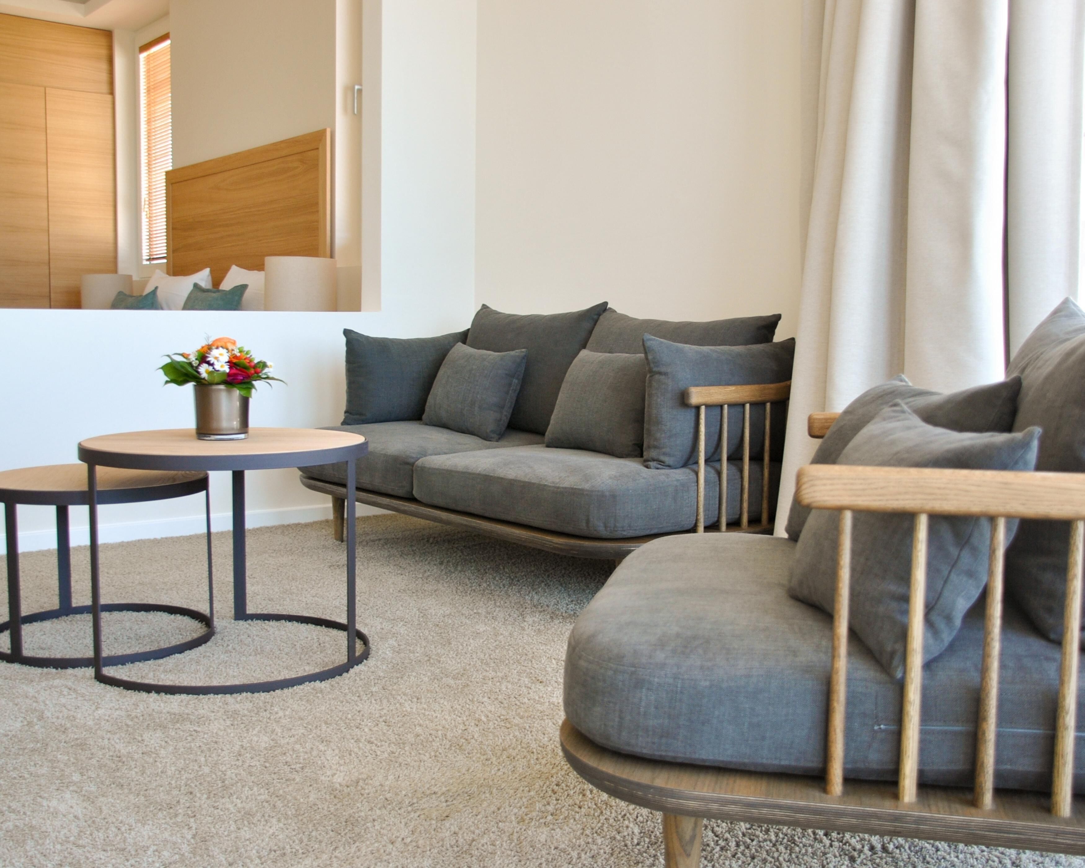 A modern living room with a grey sectional sofa, two round tables, and a small side table.