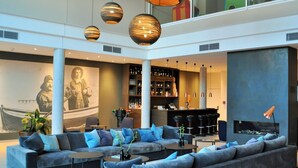 A modern lobby with a seating area, a bar, and a mural. - SeeHuus Lifestyle Hotel (Timmendorfer Strand)