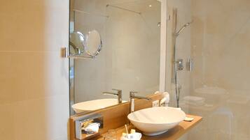 A modern bathroom with a large mirror, a sink, and a shower.