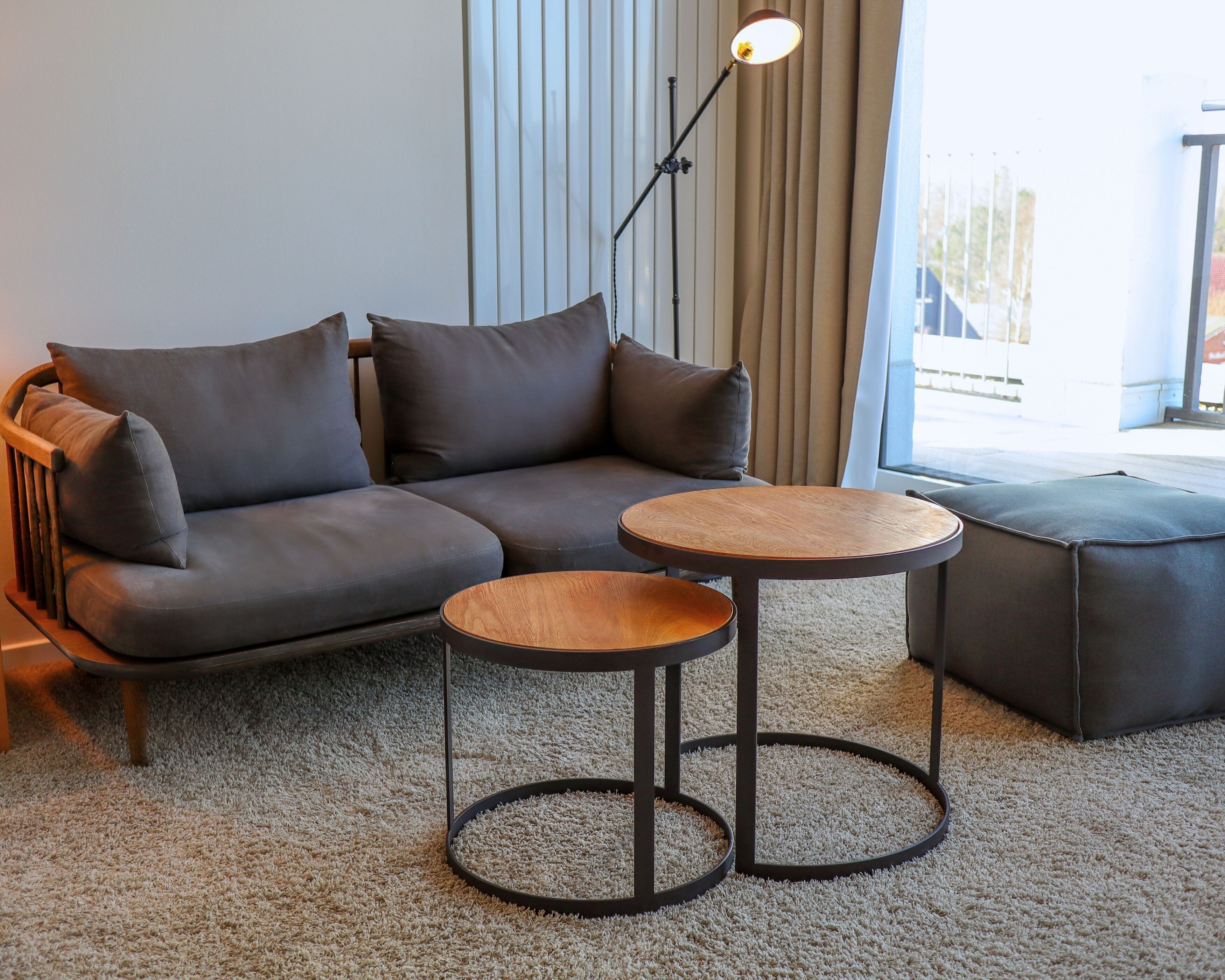 A modern living room with a sectional sofa, a round wooden coffee table, and a floor lamp.