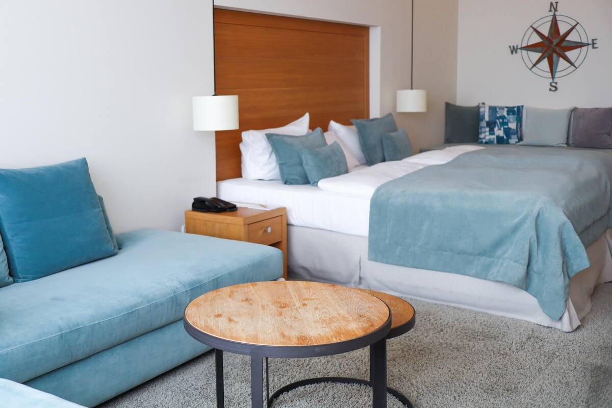 Ein Hotelzimmer mit einem Bett, einer Couch, einem kleinen Tisch und einer Wandlampe.