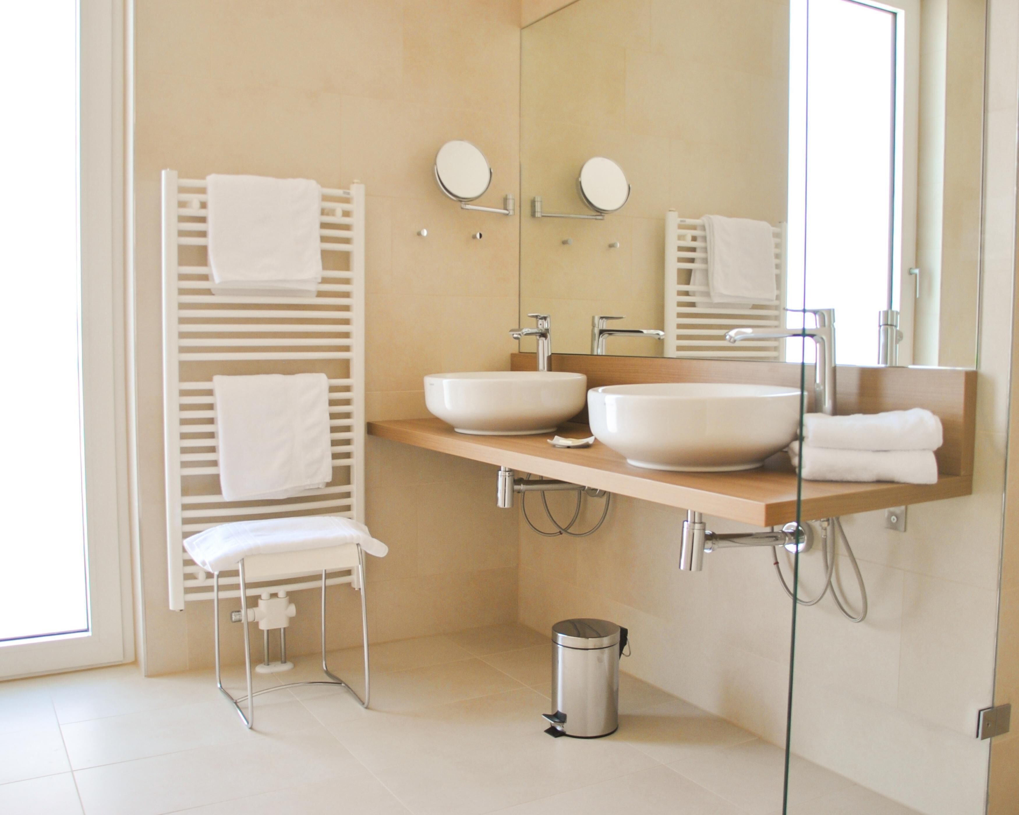 A modern bathroom with two sinks, a mirror, and a towel rack.