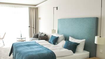 A modern hotel room with a large bed, bedside tables, a chair, and a lamp.