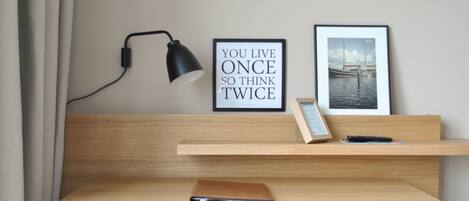 A wooden desk with a laptop, a framed quote, a picture frame, and a lamp.