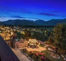 A resort with a hot tub, outdoor seating, and a view of mountains.
