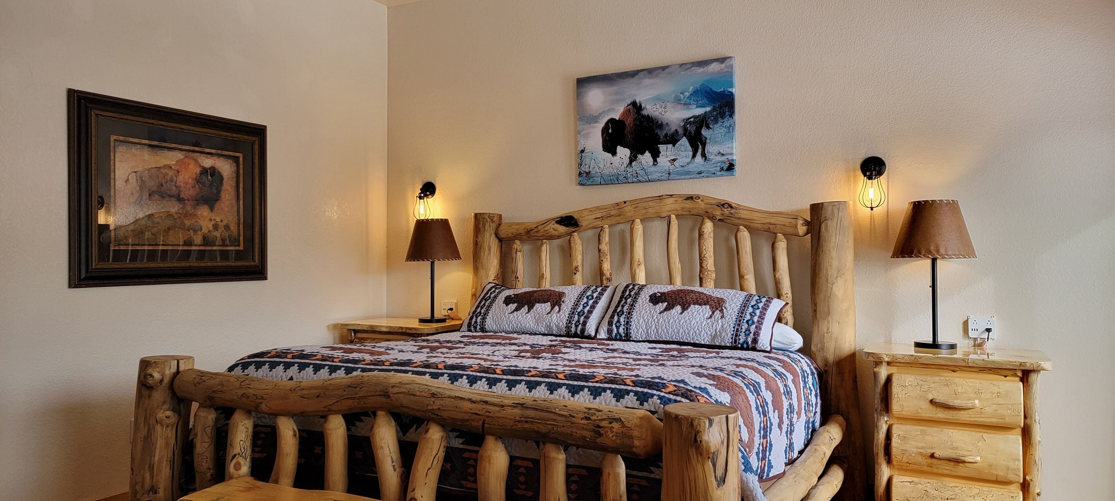 A rustic wooden bed with a patterned quilt, two bedside lamps, and a wall-mounted painting.