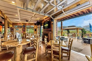 A restaurant with wooden interiors, a fireplace, and outdoor seating with a mountain view. - The Gateway Inn (Grand Lake)