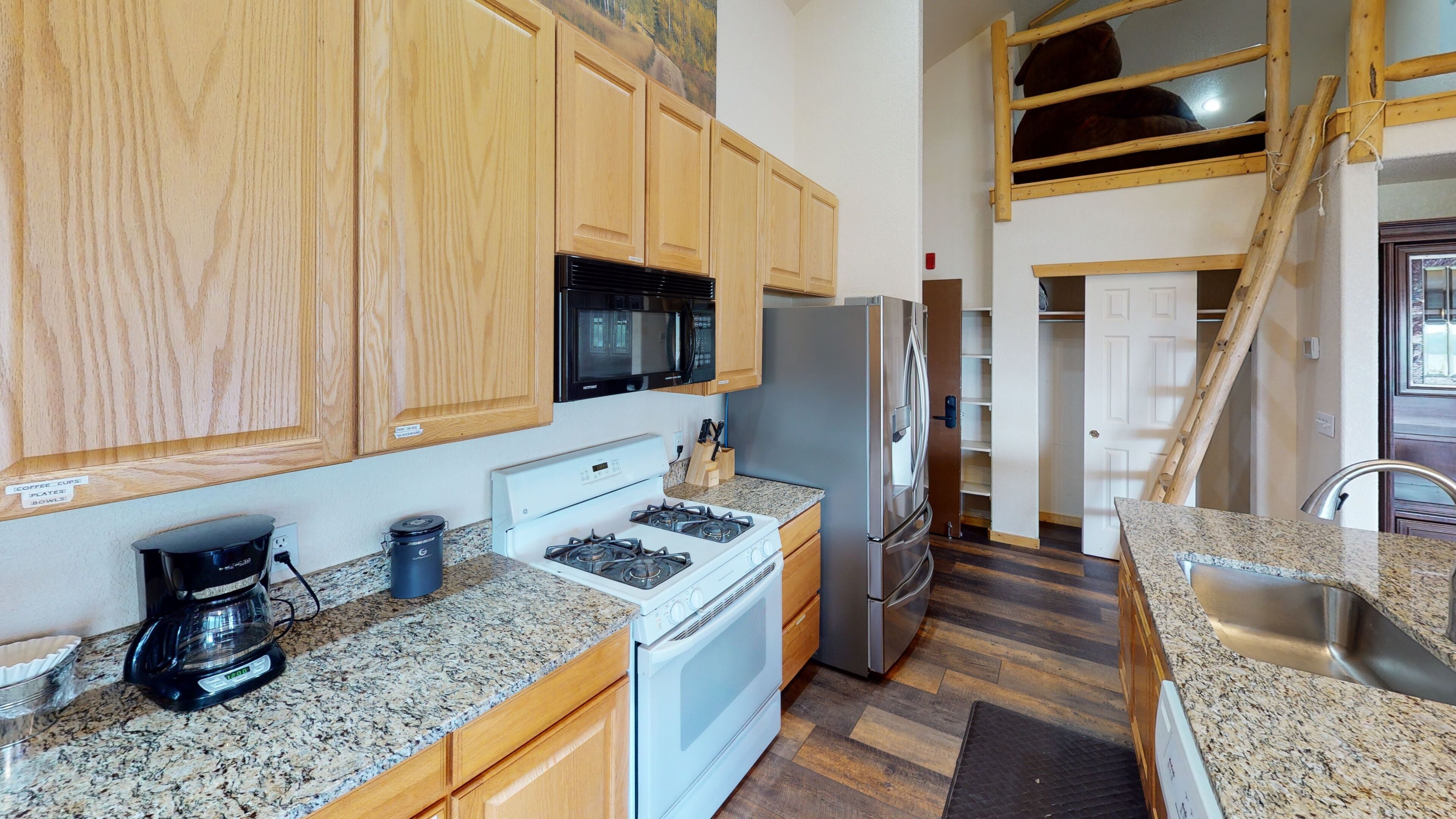 A compact kitchen with wooden cabinets, a microwave, a stove, and a refrigerator.