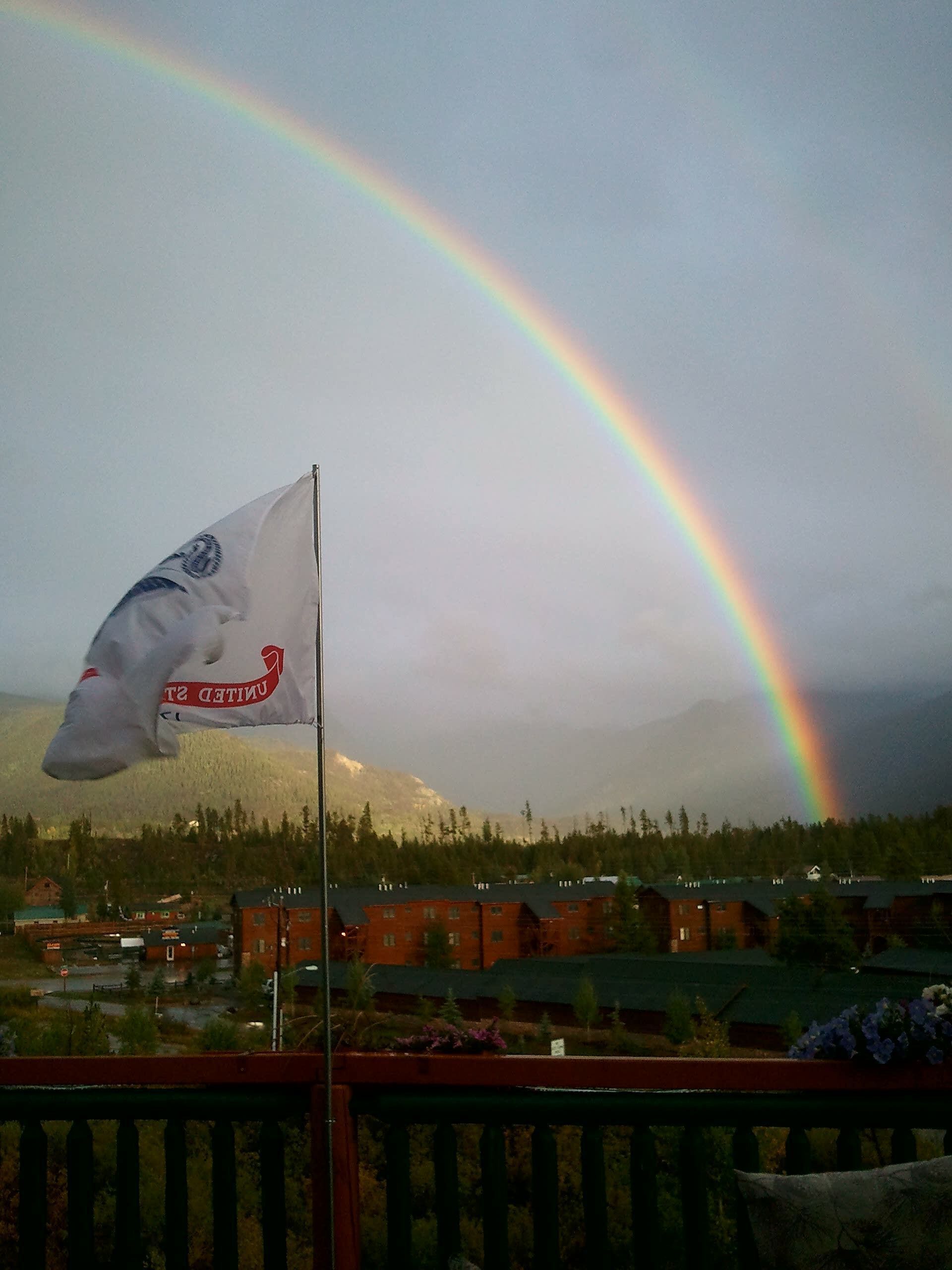 A flag with a mountain and a rainbow in the background.