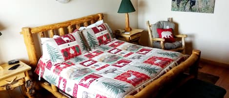 A cozy room with a wooden bed, a nightstand, a chair, and a lamp.