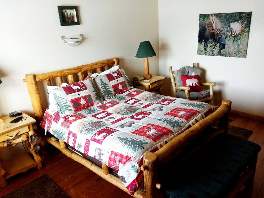 Una habitación acogedora con una cama de madera, una mesita de noche, una silla y una lámpara.