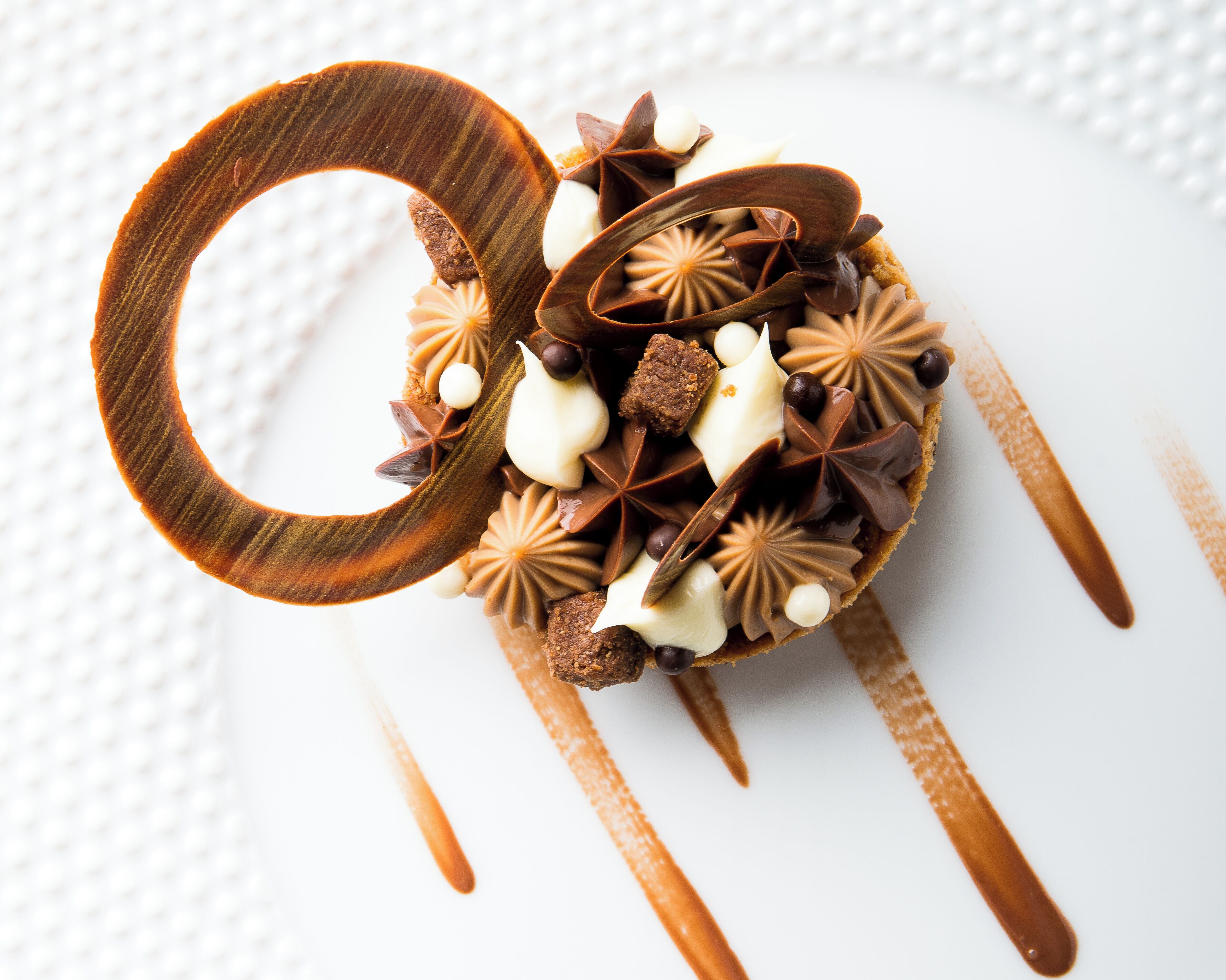 Ein Dessert mit Schokolade und weißen Elementen auf einem weißen Teller.