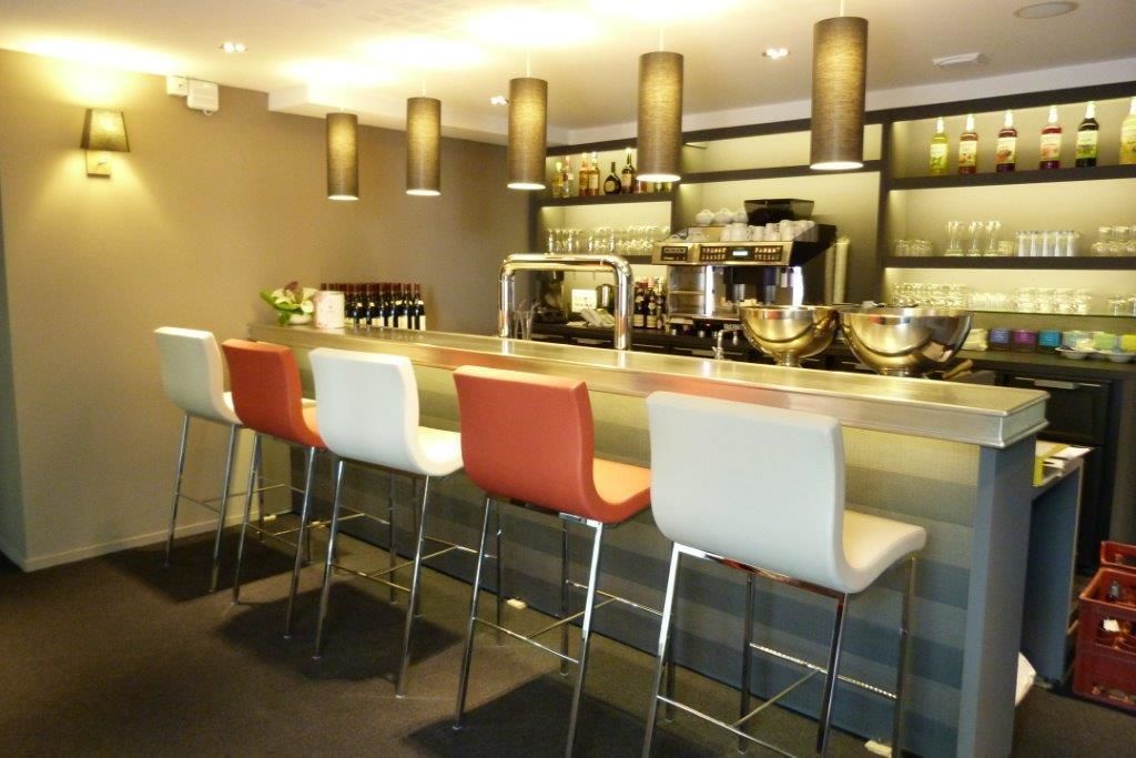 A bar area with a counter, stools, and a coffee machine.