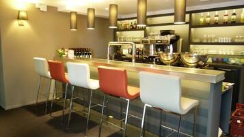 A bar area with a counter, stools, and a coffee machine.
