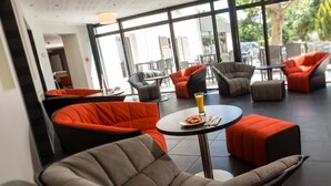 A modern indoor seating area with cushioned chairs and tables, large windows, and a view of the outdoors. - Le Cottage de Clairefontaine (Chonas-l'Amballan)