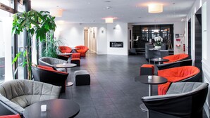 A modern lounge area with seating arrangements, including sofas and chairs, and a large potted plant. - Le Cottage de Clairefontaine (Chonas-l'Amballan)