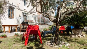 A courtyard with outdoor seating, a barbecue grill, and a tree. - La Gemma di Elena (Lucca)