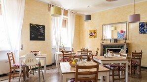 A dining area with multiple tables and chairs, a fireplace, and artwork on the walls. - La Gemma di Elena (Lucca)