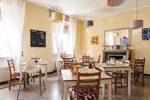 Un'area pranzo con diversi tavoli e sedie, un camino e opere d'arte alle pareti.