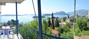 A balcony with a table and chairs overlooking a lake with mountains in the background. - Gianna Studios (Lefkada)