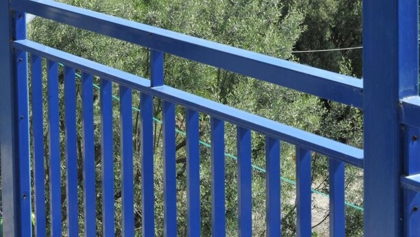 Un balcon offrant une vue sur un paysage côtier, avec des arbres, des maisons et la mer.