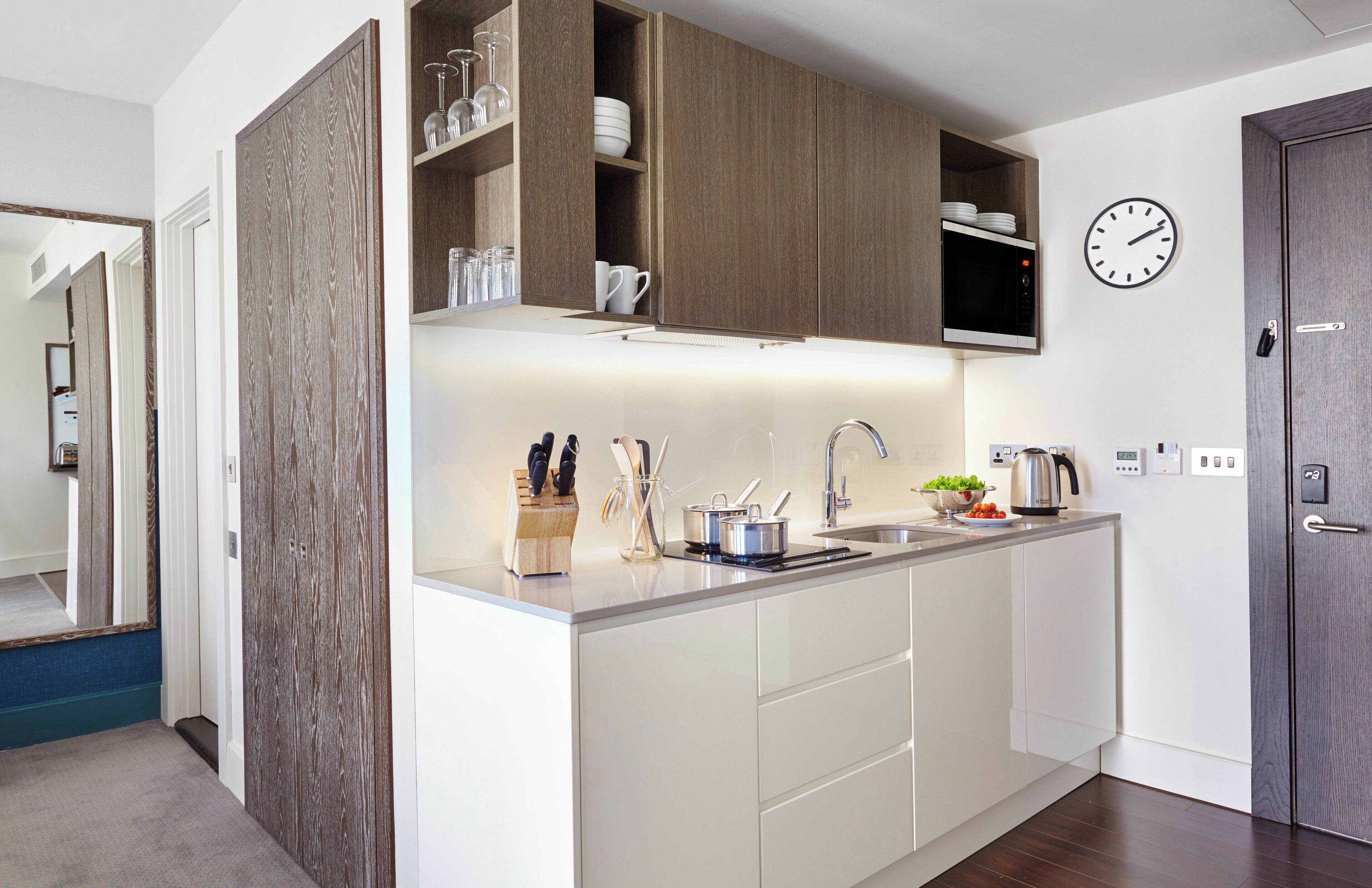 Una cocina moderna con armarios blancos, un microondas integrado y un lavabo.