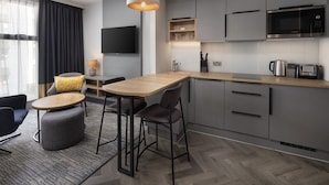 A modern kitchen with grey cabinets, a wooden countertop, a built-in microwave, and a coffee machine. - Staybridge Suites London - Vauxhall by IHG (London)