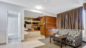 A living room with a sofa, a coffee table, and a bathroom visible through an open door. - Deluxe Inn (Toronto)
