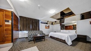 A hotel room with a bed, a sofa, a small table, and a mirror. - Deluxe Inn (Toronto)