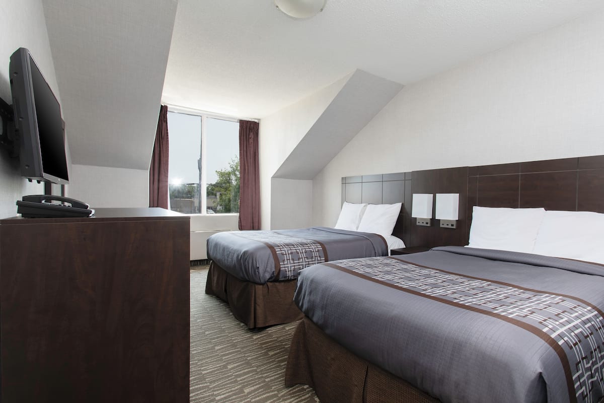 Una habitación de hotel con dos camas, televisor y escritorio.