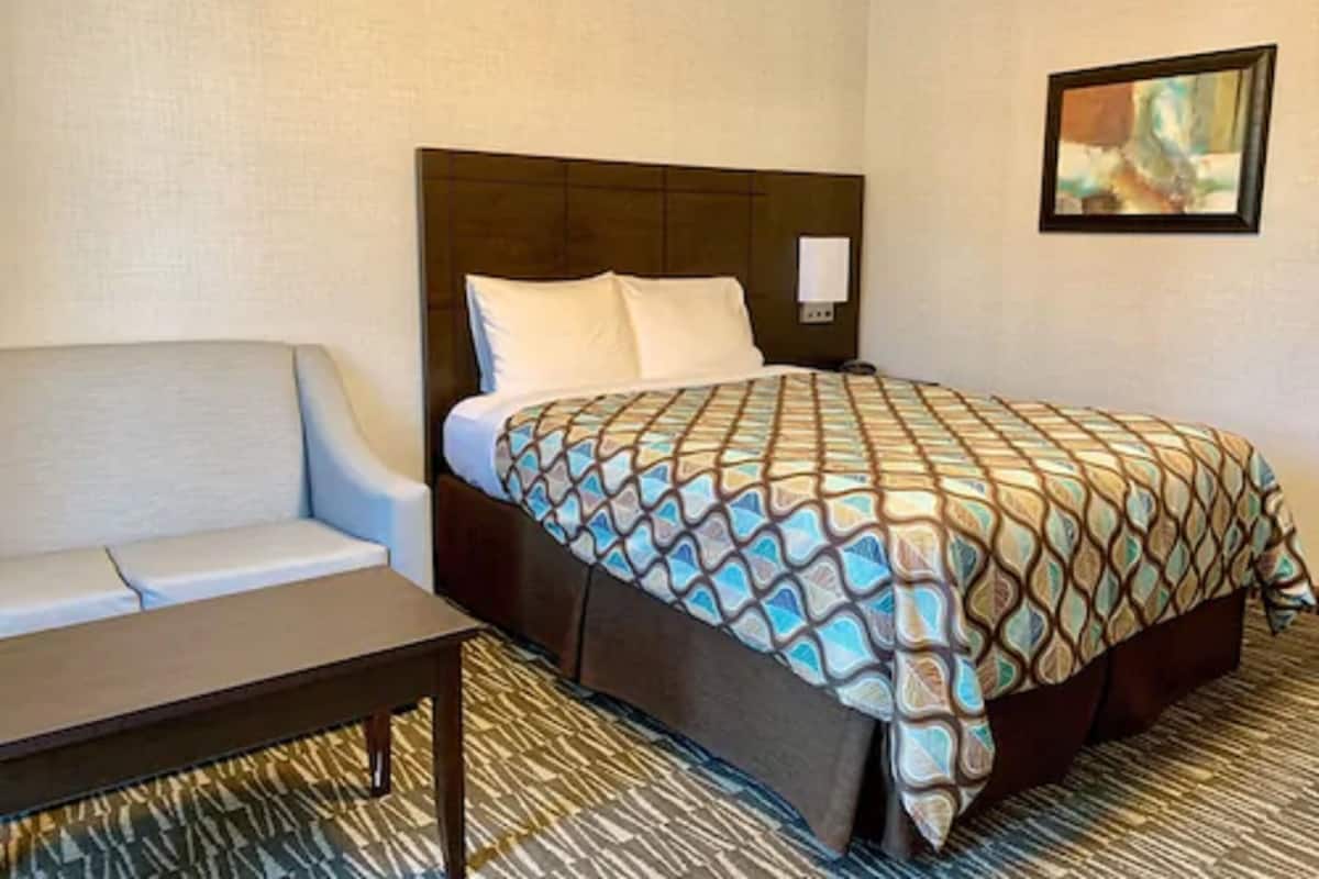 Una habitación de hotel con una cama, un sofá, una mesita y un cuadro en la pared.
