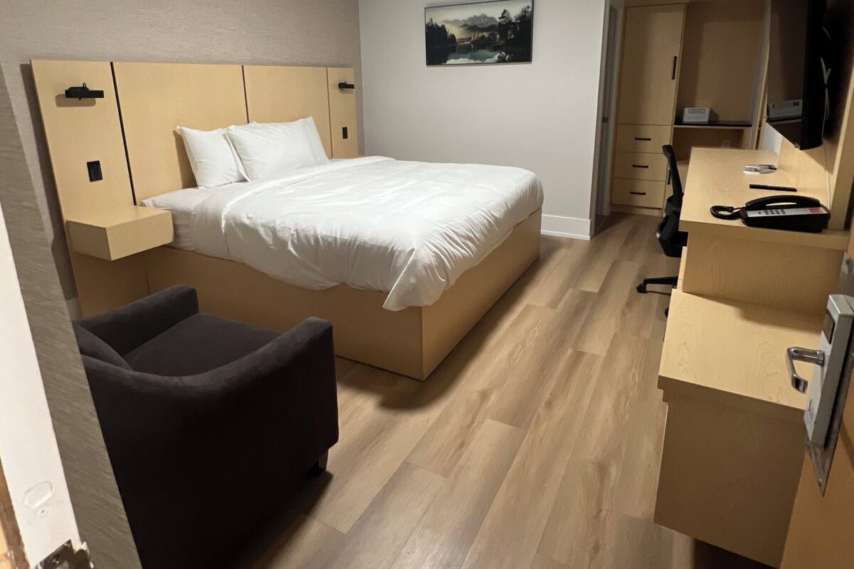 Habitación de hotel con cama, escritorio, silla, televisor y un cuadro en la pared.