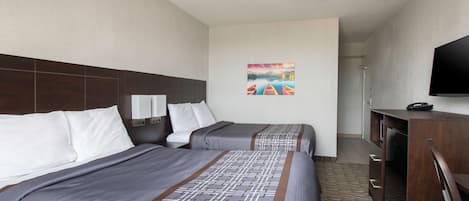 A hotel room with two beds, a flat-screen TV, a painting on the wall, and a desk with a chair.