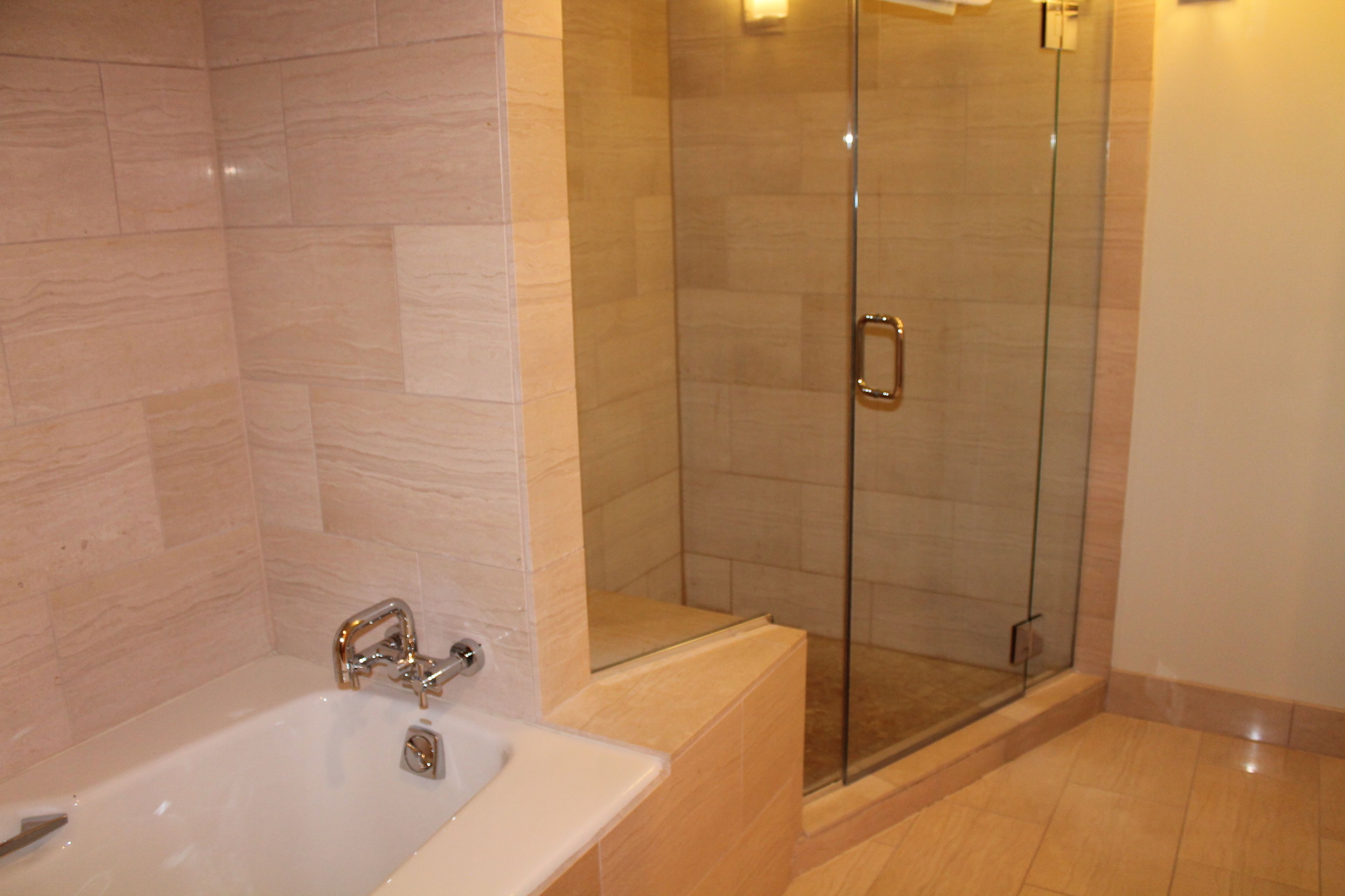A modern bathroom with a glass-enclosed shower, a standalone bathtub, and a tiled floor.