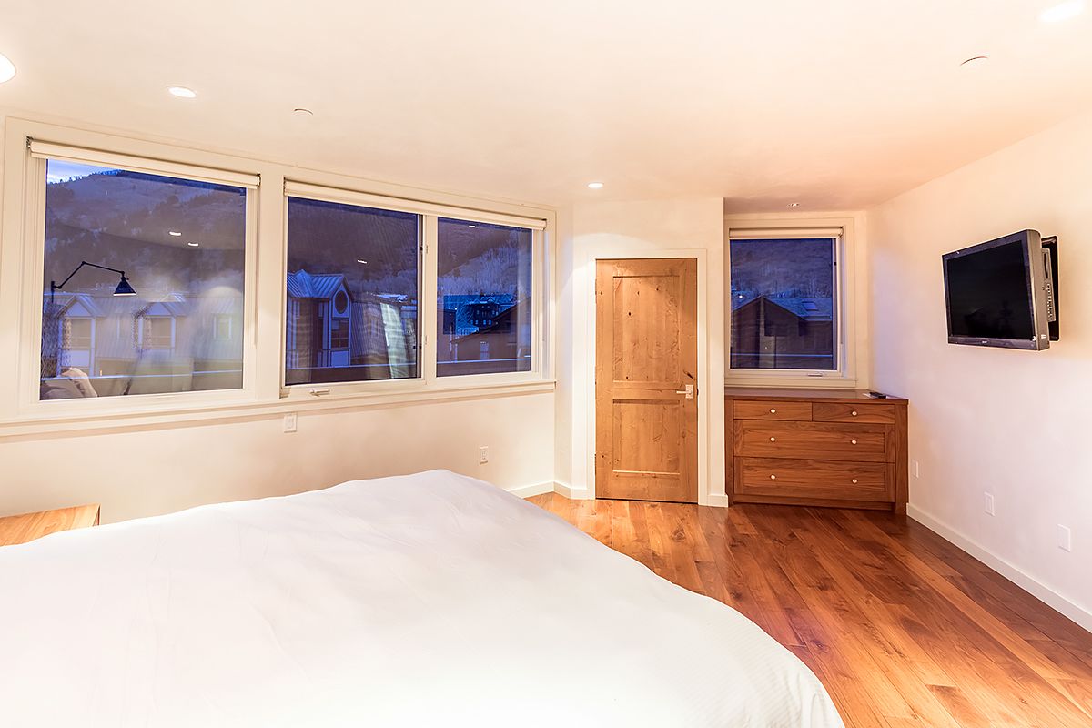Makuuhuoneessa on suuri sänky, puinen lipasto ja kaksi ikkunaa.