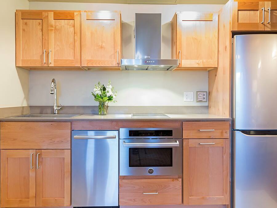 Une cuisine moderne avec des meubles en bois, des appareils électroménagers en acier inoxydable et un four encastré.