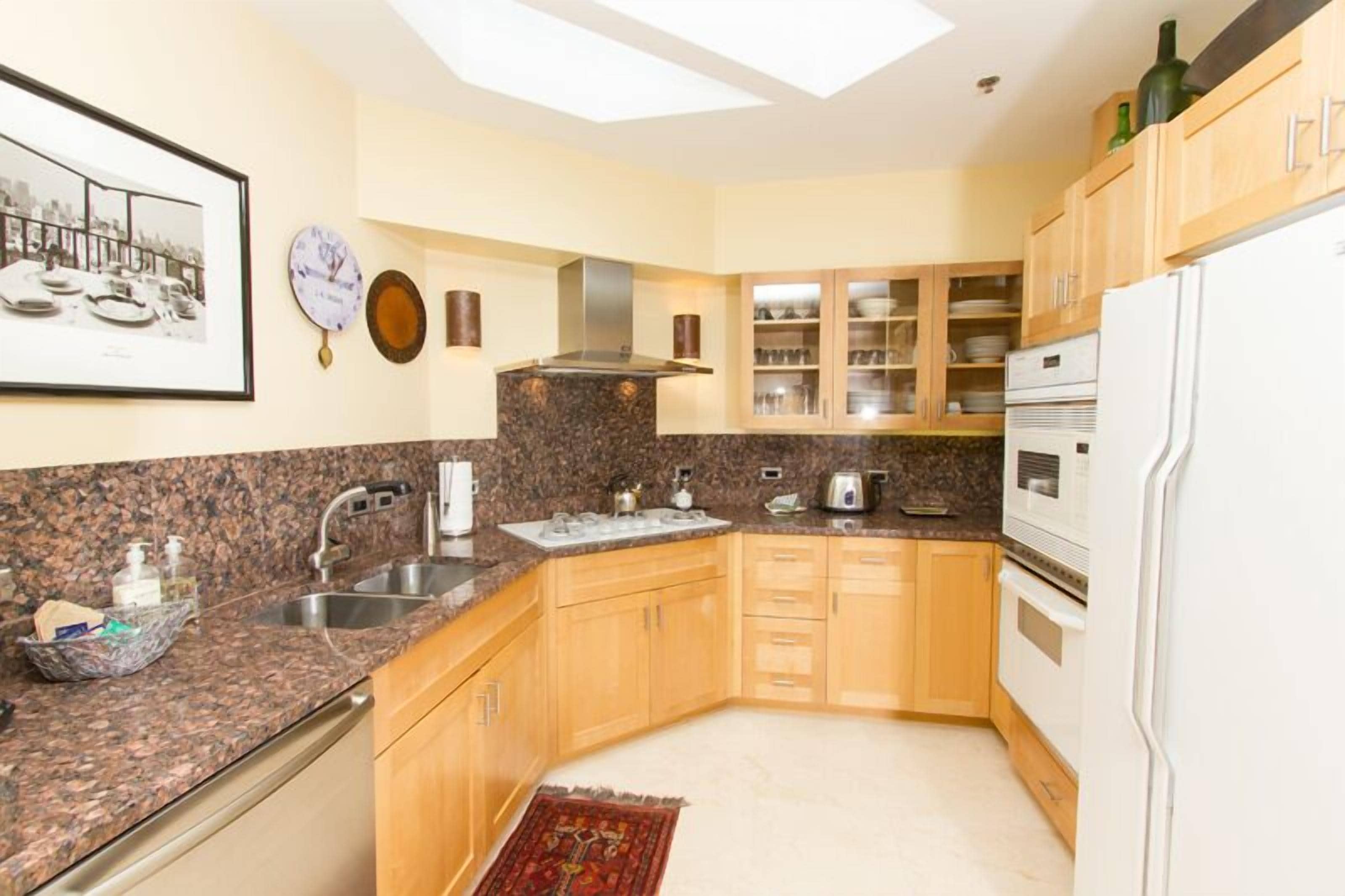 A kitchen with granite countertops, wooden cabinets, a built-in oven, and a refrigerator.
