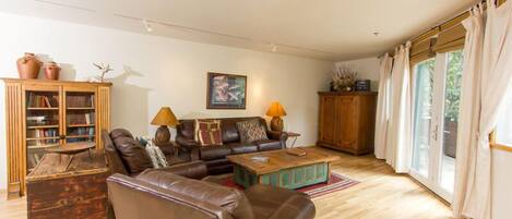 A living room with a leather sofa, two lamps, a wooden cabinet, and a bookshelf.