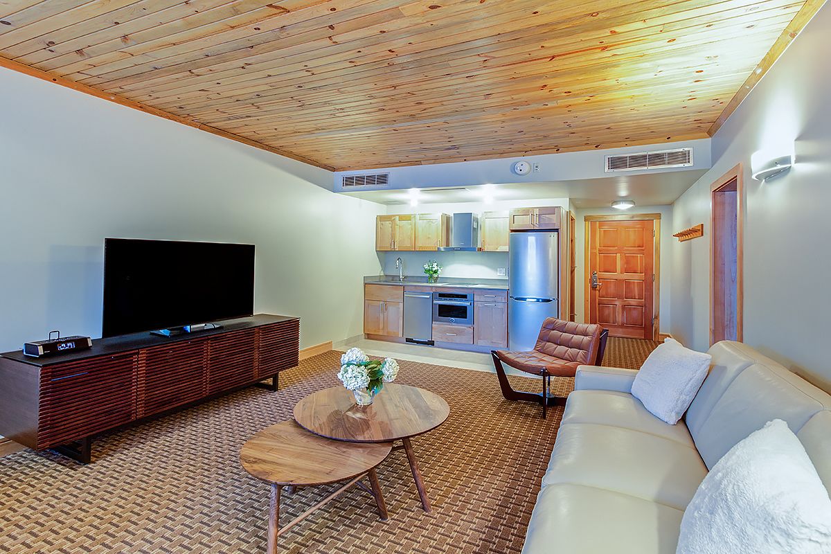 A modern living room with a flat-screen TV, a wooden entertainment unit, a round coffee table, and a sofa.