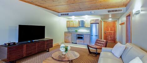 A modern living room with a flat-screen TV, a wooden entertainment unit, a round coffee table, and a sofa.